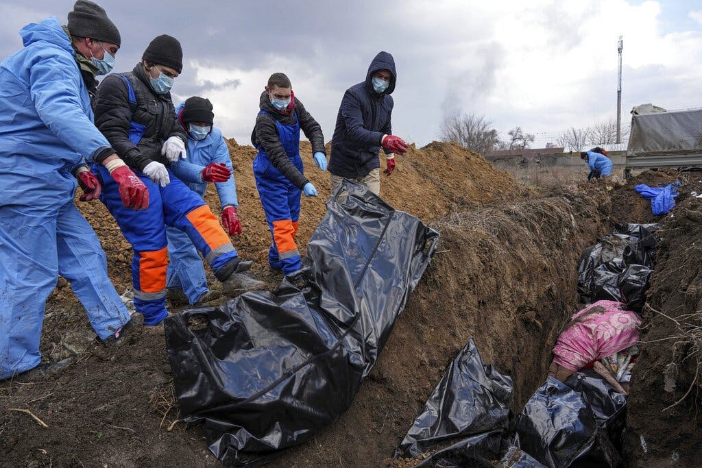 Bodies are placed into a mass grave on the outskirts of Mariupol, Ukraine, March 9, 2022. AP/Evgeniy Maloletka