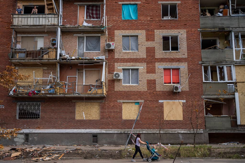 A woman pushes a baby stroller near a building damaged during a Russian attack in Slovyansk, eastern Ukraine, Saturday, June 4, 2022. (AP Photo/Bernat Armangue)