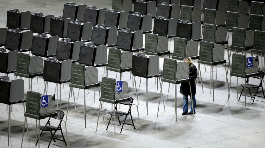 A woman votes alone among a large group of stations at the Cross Insurance Center during Maine's presidential primary elections Tuesday.