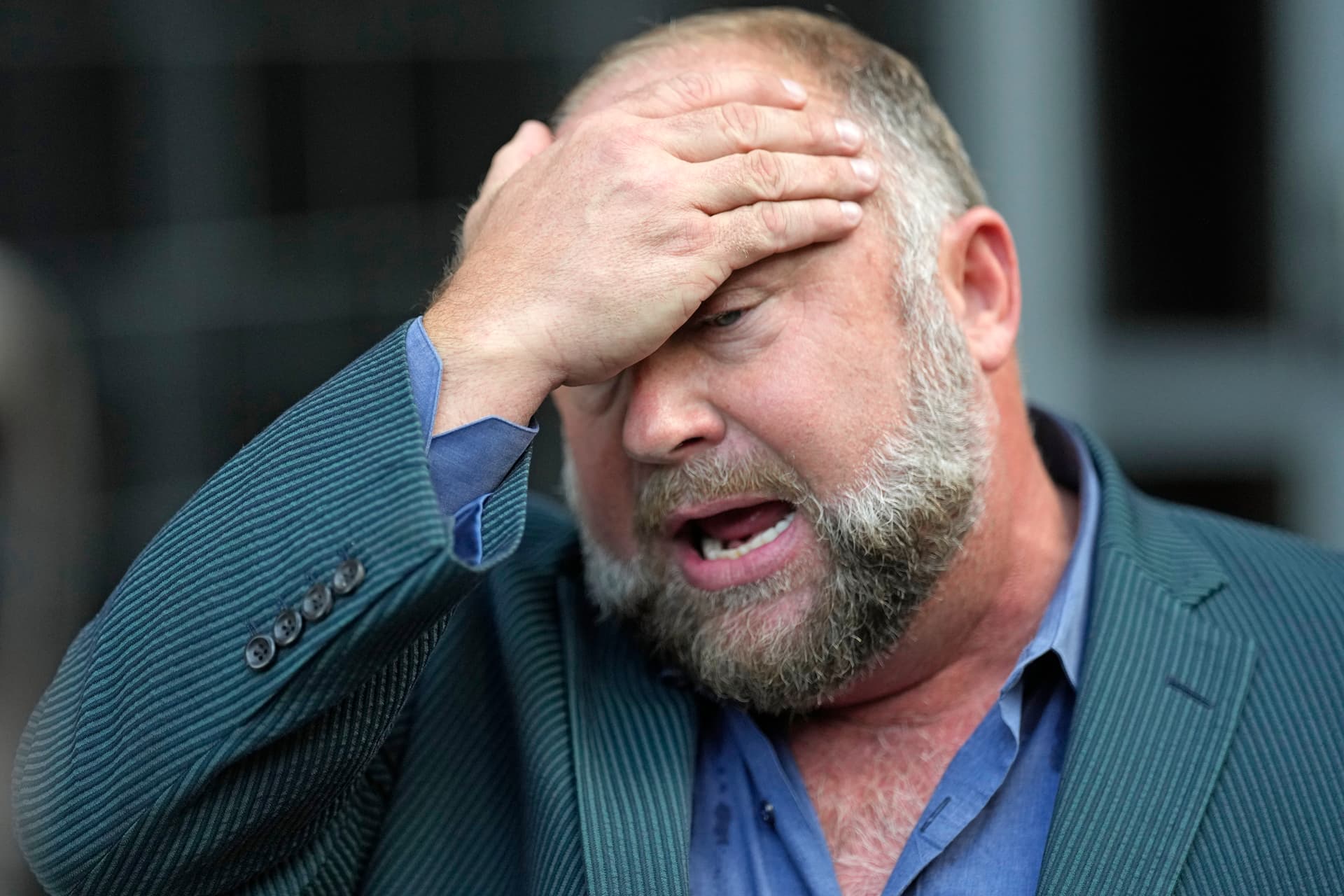 Alex Jones wipes his forehead as he speaks to the media after arriving at the federal courthouse for a hearing in front of a bankruptcy judge Friday, June 14, 2024, at Houston. 