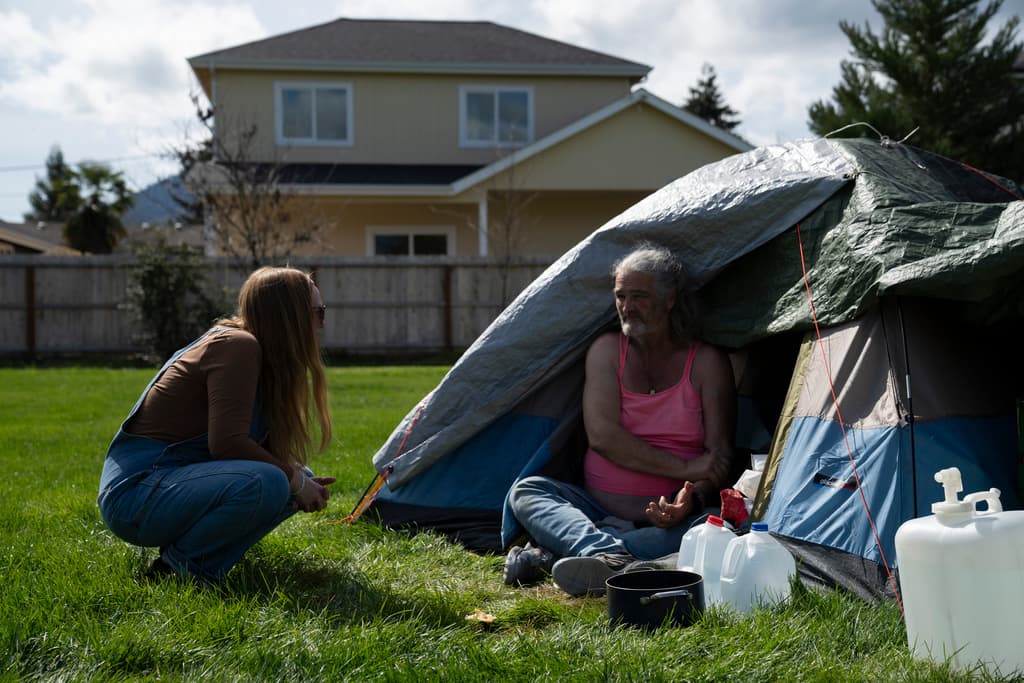A nurse leads a group of volunteers working in a homeless encampment.