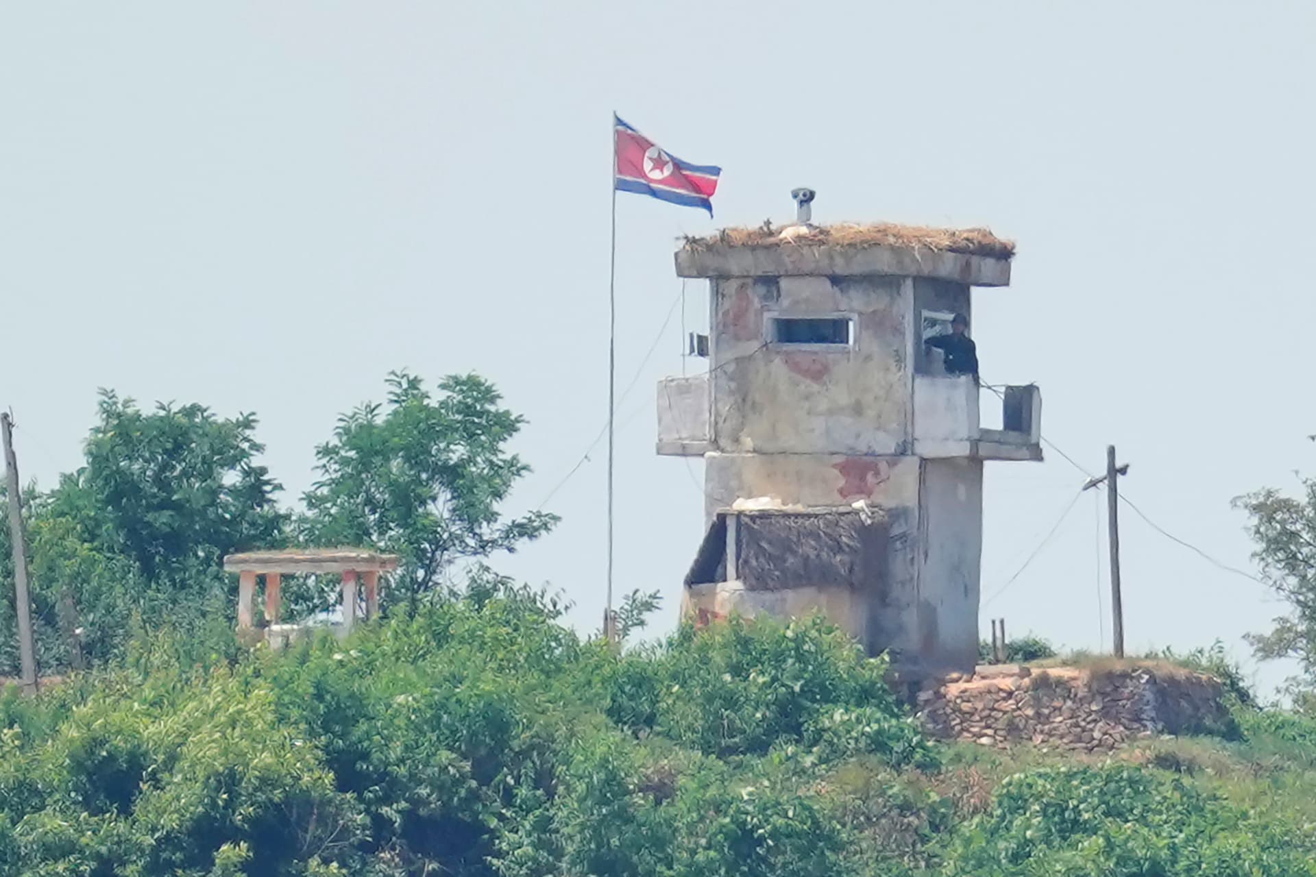 A soldier stands at a North Korean military guard post flying a national flag, seen from Paju, South Korea.