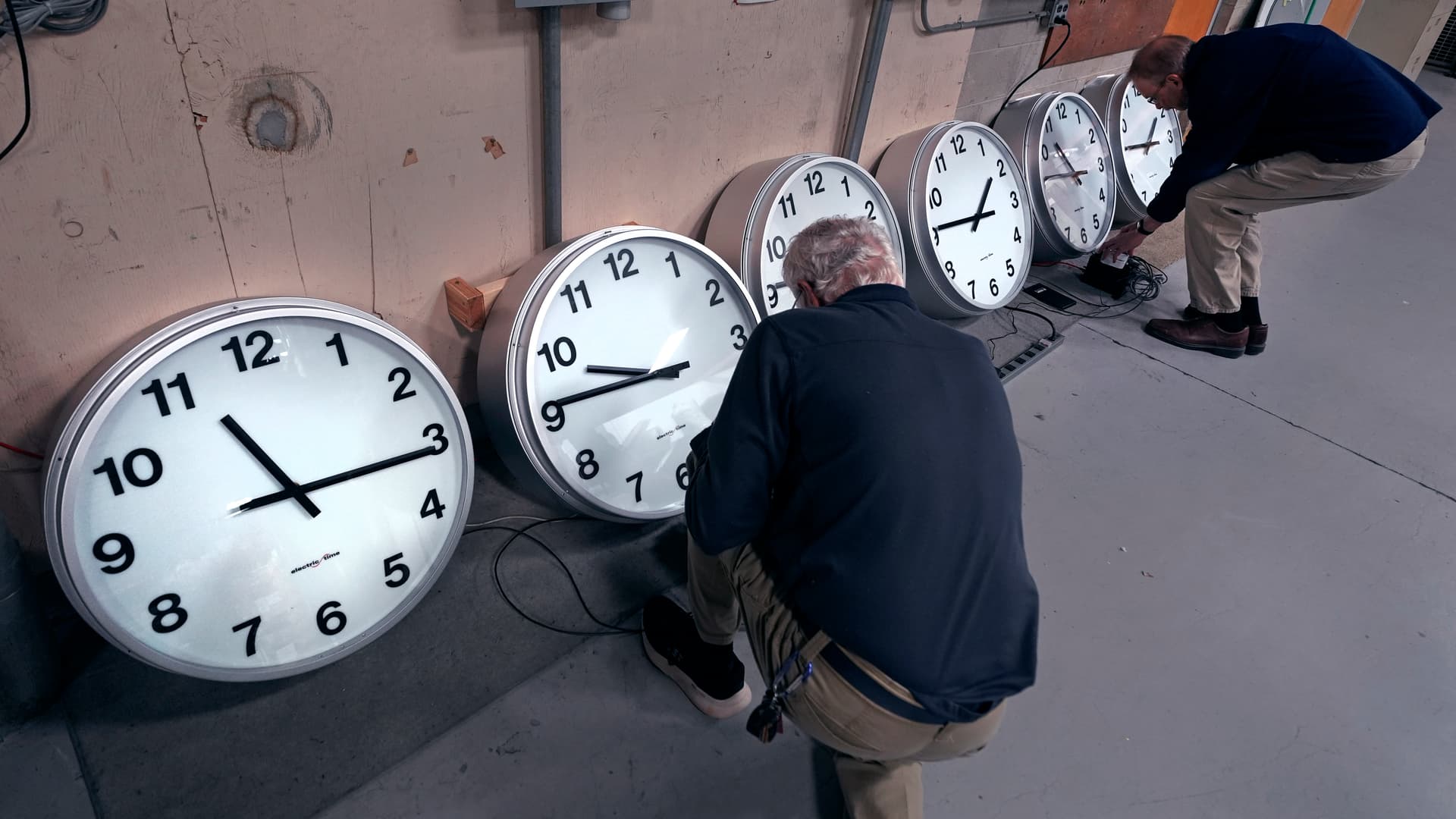 Clockmakers Rich Finn, left, and Tom Erb adjust the time zone controllers on a series of clocks for Paine Field at Everett, Washington a few days before Daylight Saving 2024.