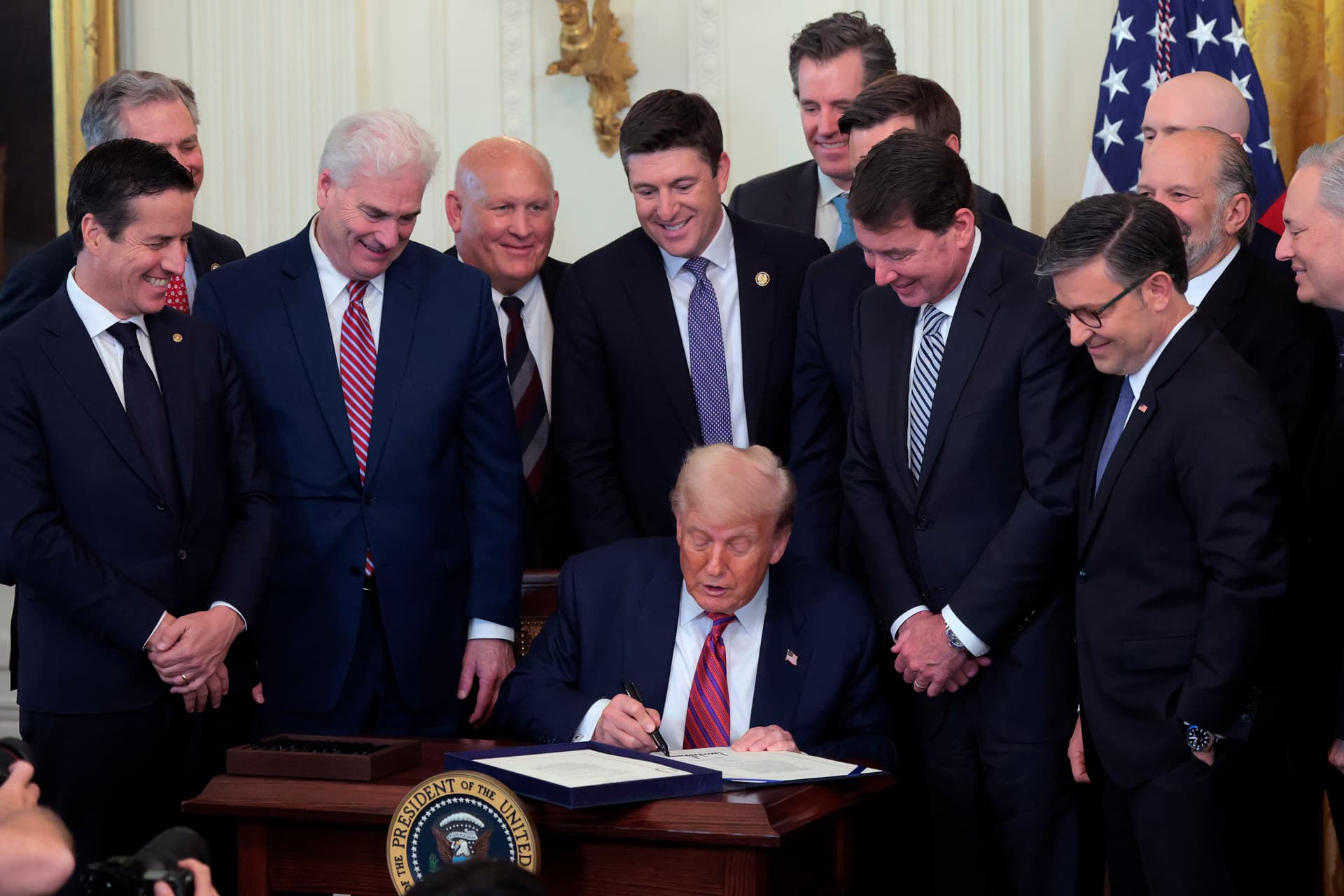 President Trump, surrounded by lawmakers, signs the 'GENIUS Act' into law during a ceremony in the East Room of the White House on July 18, 2025.