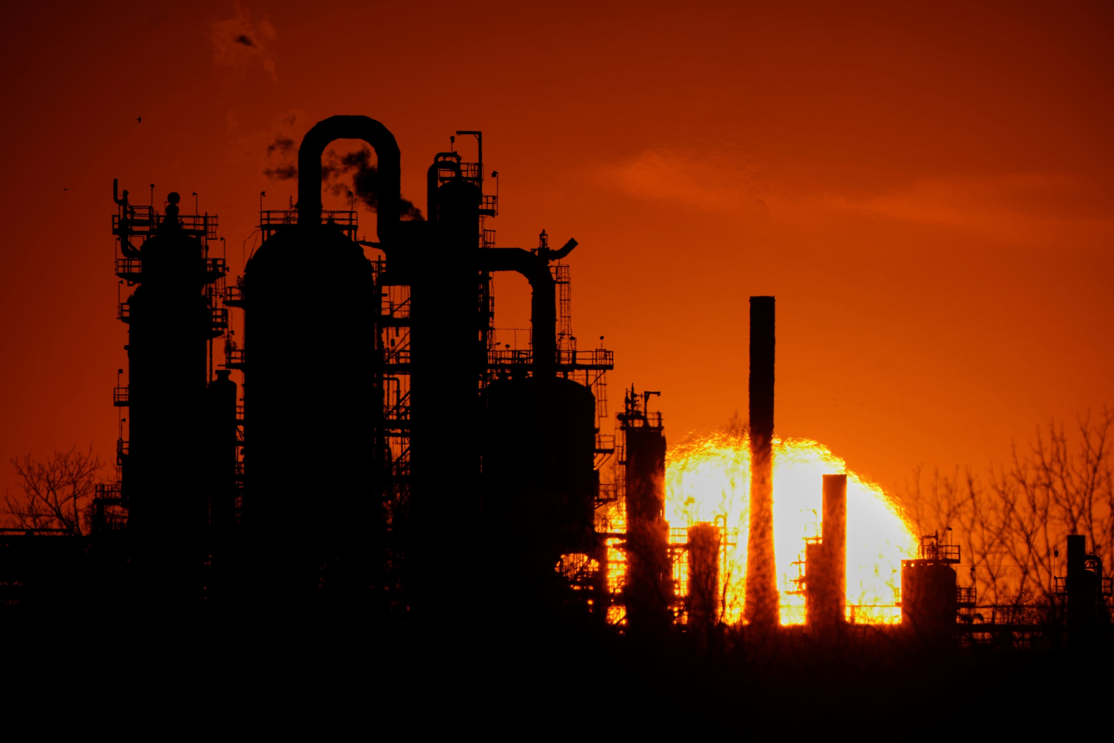 The HF Sinclair El Dorado oil refinery is silhouetted against the sky at sunset, March 21, 2025.