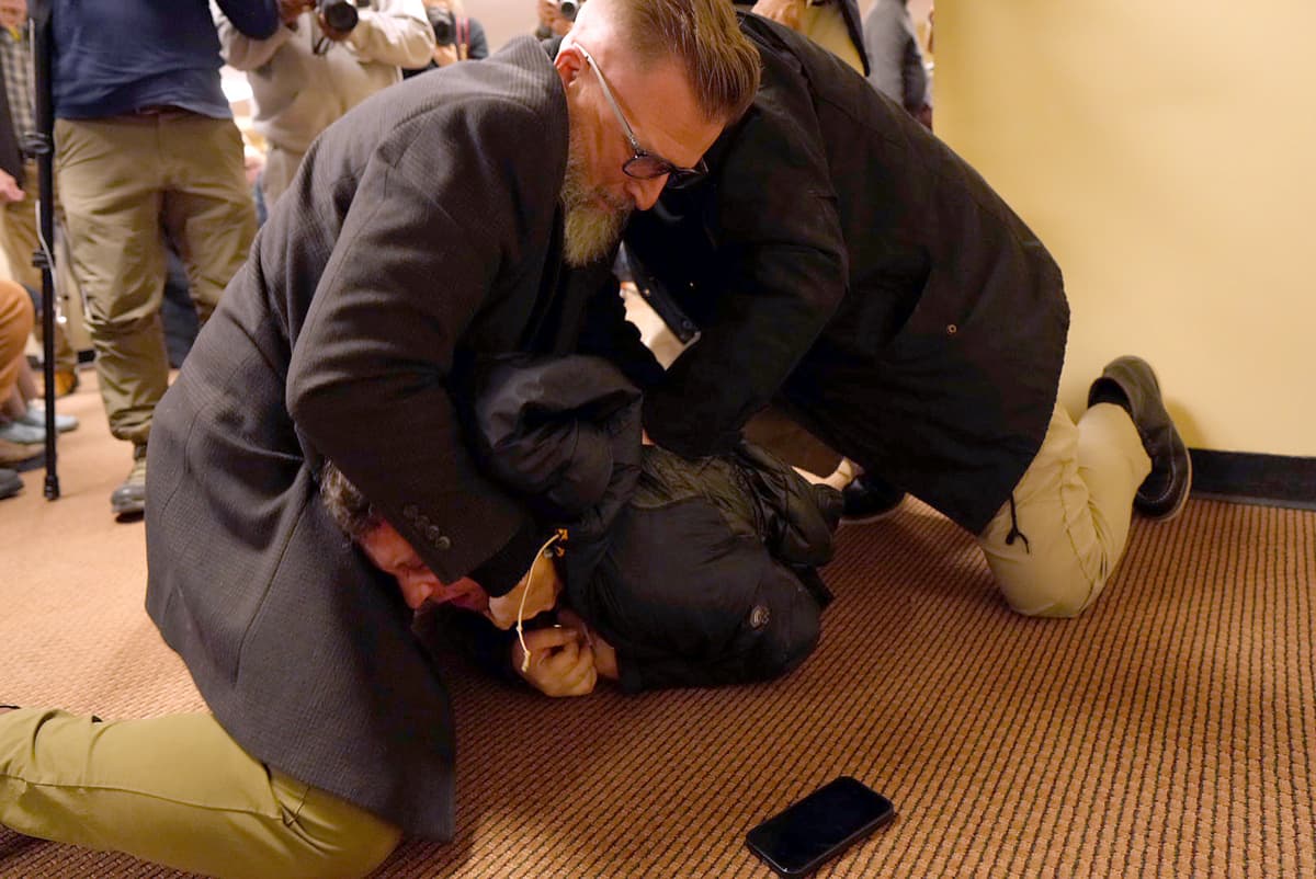 A man is tackled to the ground after spraying an unknown substance on Ilhan Omar during a town hall on Tuesday, Jan. 27, 2026.