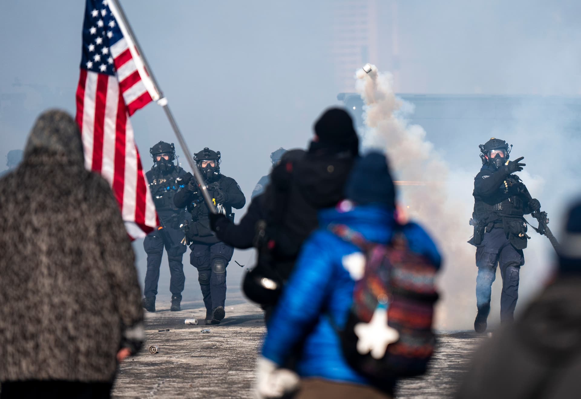 A Minneapolis Police officer throws a can of tear gas at people gathered on Nicollet Avenue after a fatal shooting by federal agents on January 24, 2026 in Minneapolis, Minnesota.