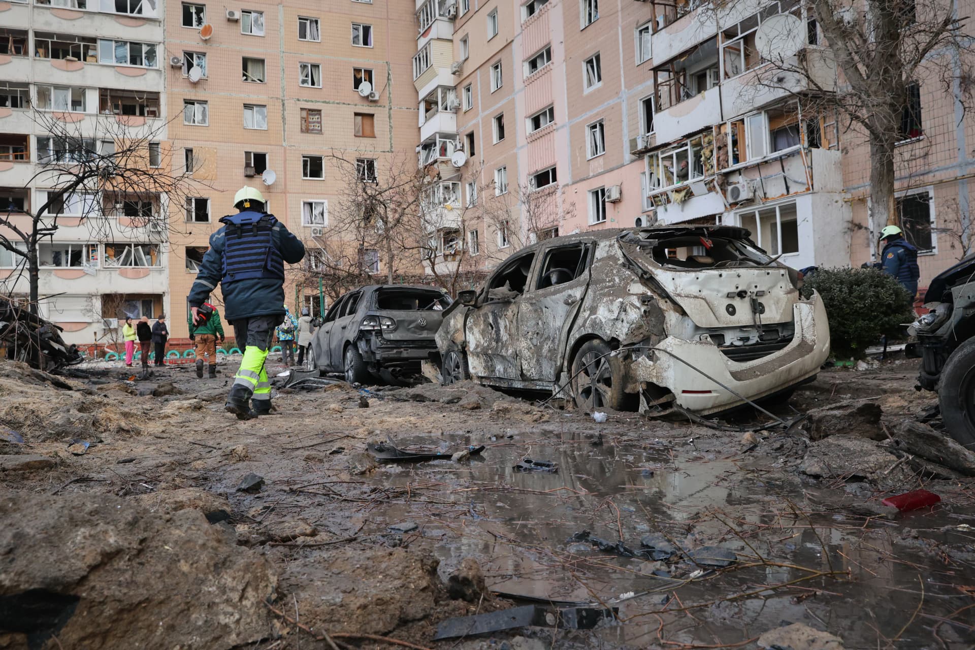 People pass by damaged cars near an apartment building after a Russian attack in Zaporizhzhia, Ukraine, Wednesday, Jan. 28, 2026.