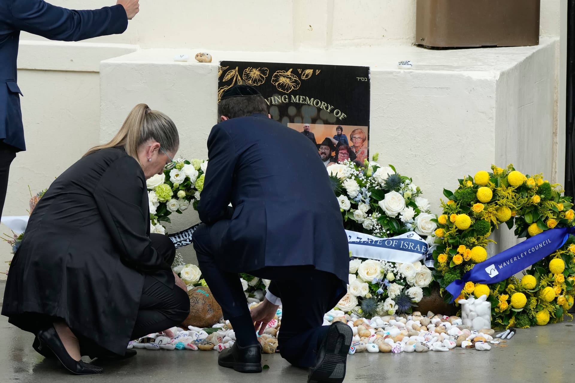 Israel's President Isaac Herzog, center, and his wife Michal Herzog, left, offer prayers February 9, 2026 at Bondi Beach where the December 2025 shooting took place.