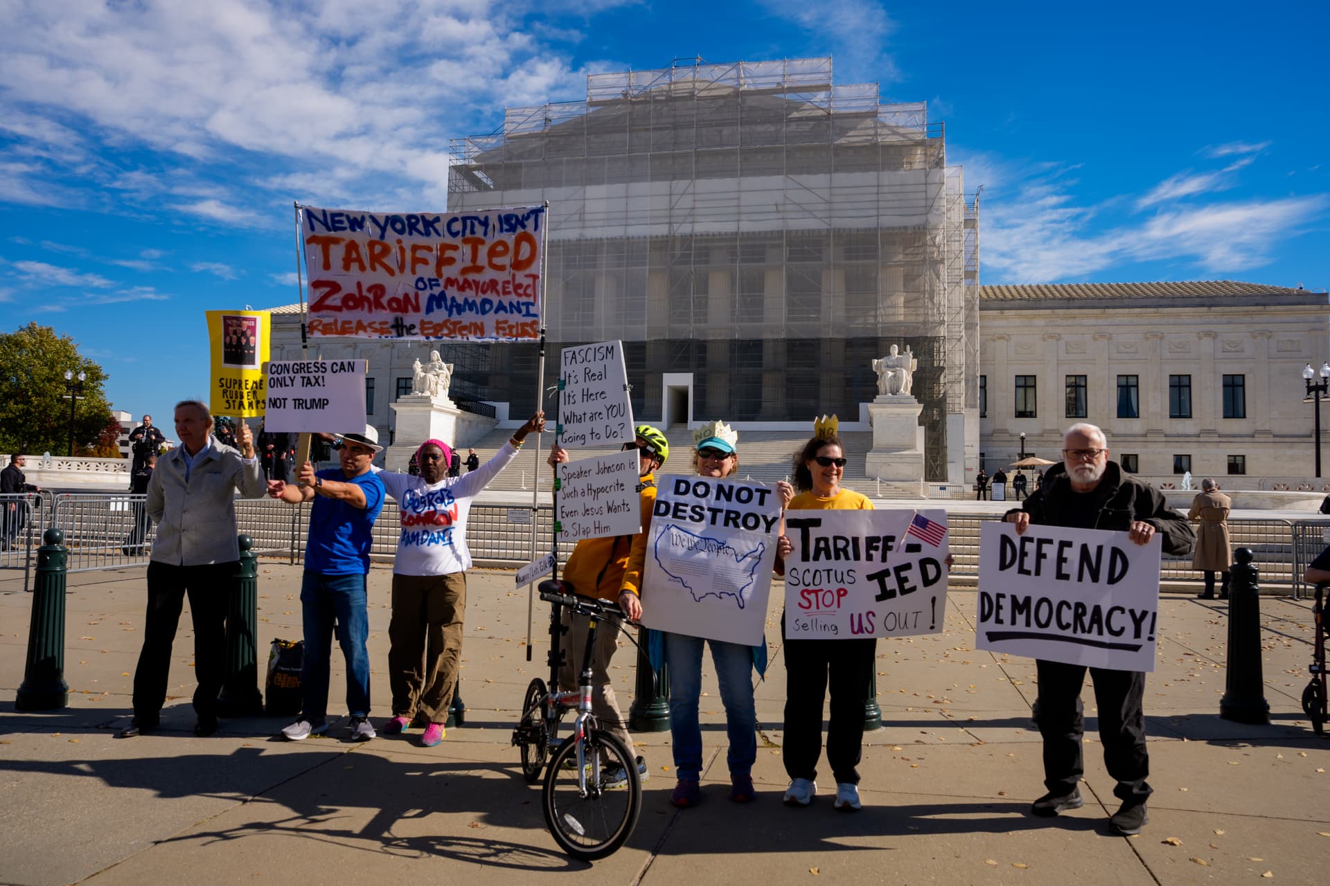 Activists pose for photographs outside the Supreme Court during arguments on the legality of the Trump administration's tariffs at Washington, D.C., on November 5, 2025. 