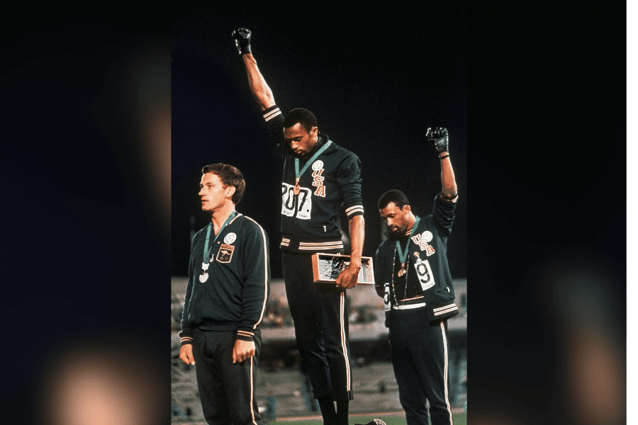 Extending gloved hands skyward in racial protest, U.S. athletes Tommie Smith, center, and John Carlos stare downward during the playing of "The Star-Spangled Banner" after Smith received the gold and Carlos the bronze medal in the 200 meter run at the Summer Olympic Games at Mexico City. 