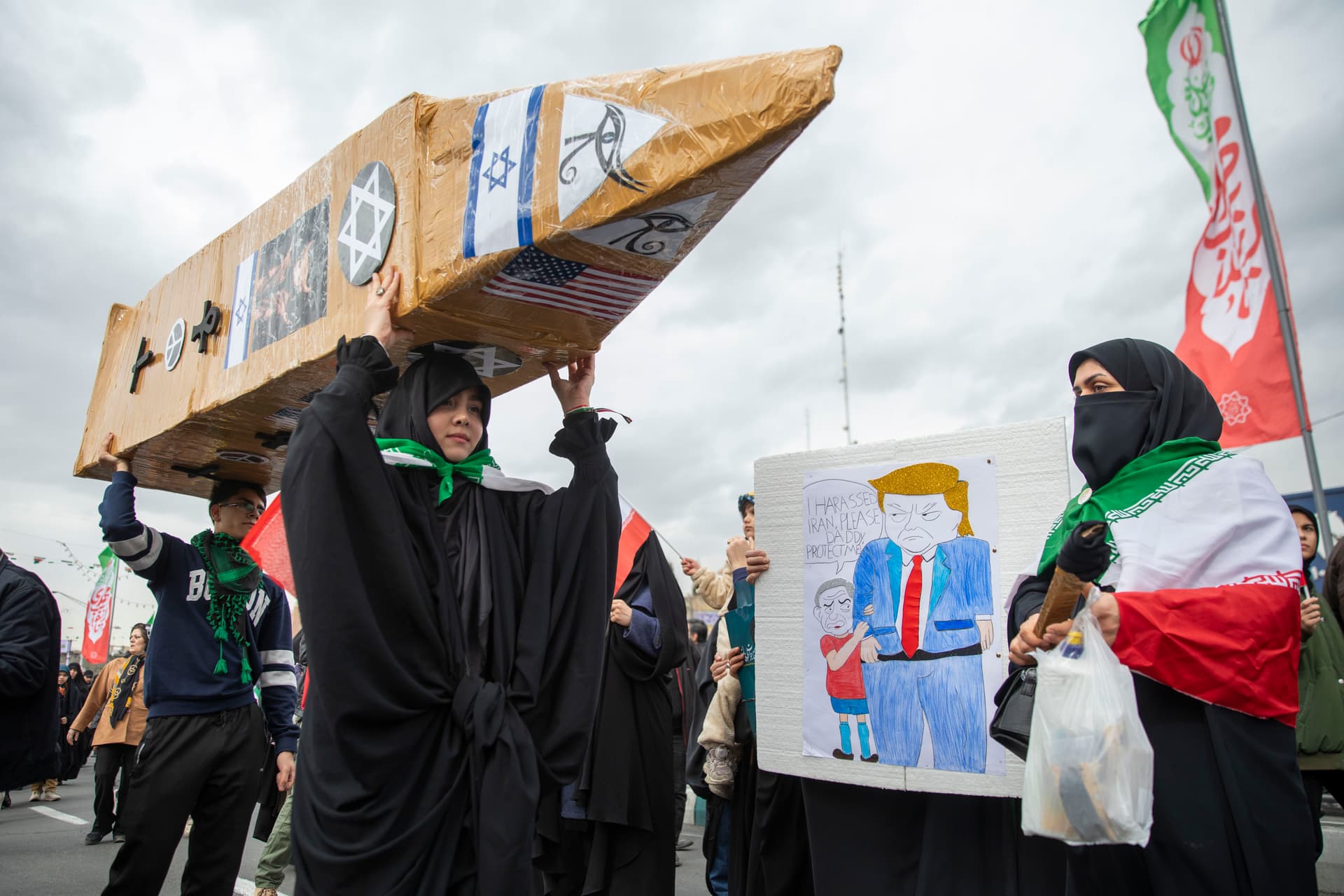 An Iranian woman carries a rocket replica while another holds a sign depicting President Trump and Prime Minister Benjamin Netanyahu of Israel during commemorations to mark the anniversary of the 1979 Iranian Revolution on February 11, 2026, at Tehran, Iran. In that year, Ruhollah Khomeini led an overthrow of the Pahlavi dynasty in 1979 and established himself as Supreme Leader of the Islamic Republic of Iran.