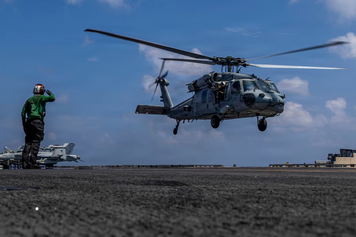 This handout image from the U.S. Navy shows Captain Daniel Keeler, the commanding officer of the Nimitz-class aircraft carrier USS Abraham Lincoln, flying an MH-60R Sea Hawk helicopter in the Indian Ocean on January 23, 2026. 