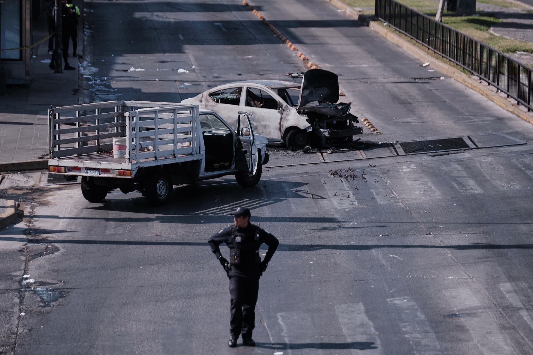 A police officer stands guard by a charred vehicle after it was set on fire, on a road in Guadalajara, Jalisco state, Mexico, Sunday.