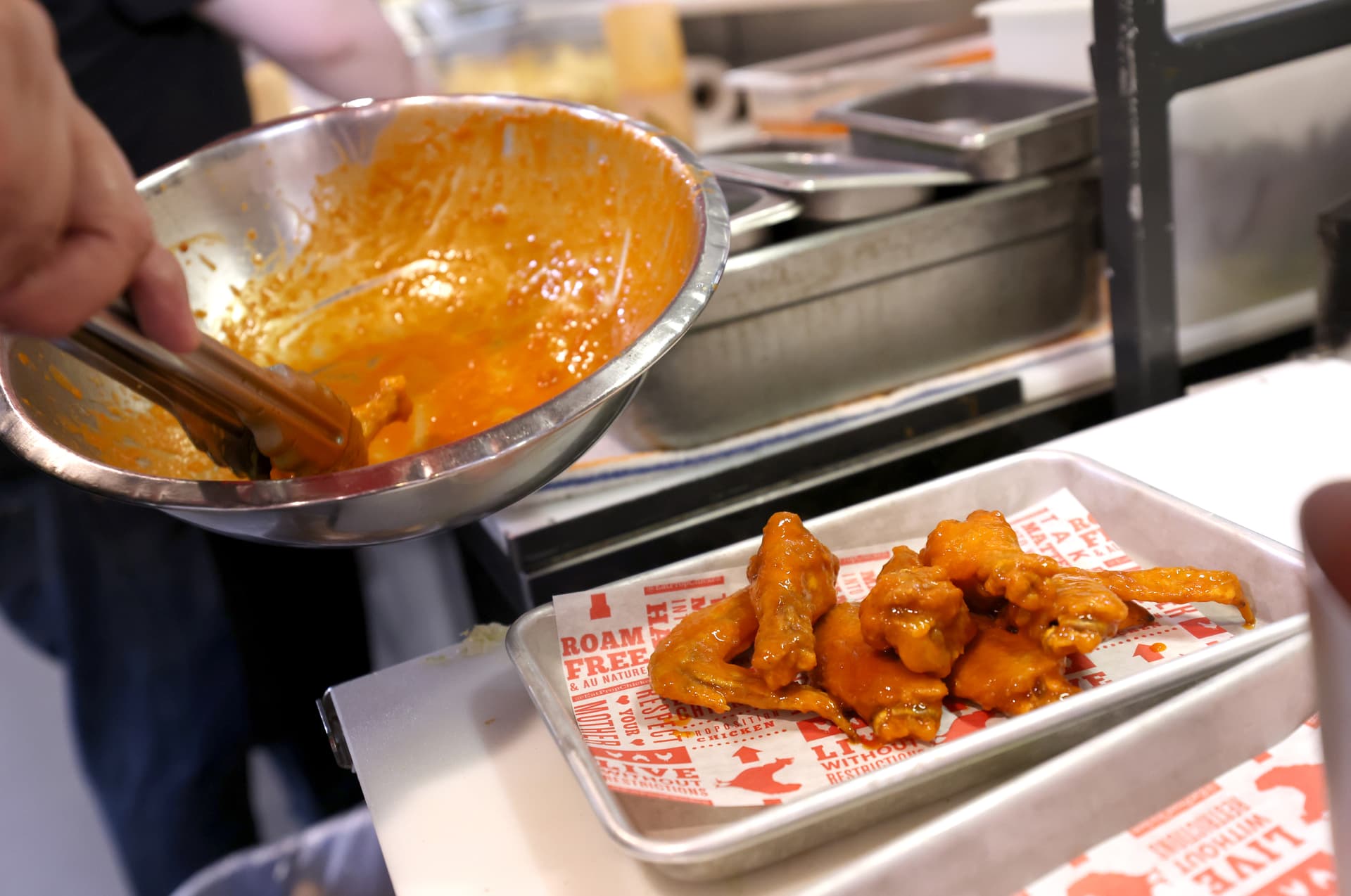 A cook prepares Buffalo chicken wings.