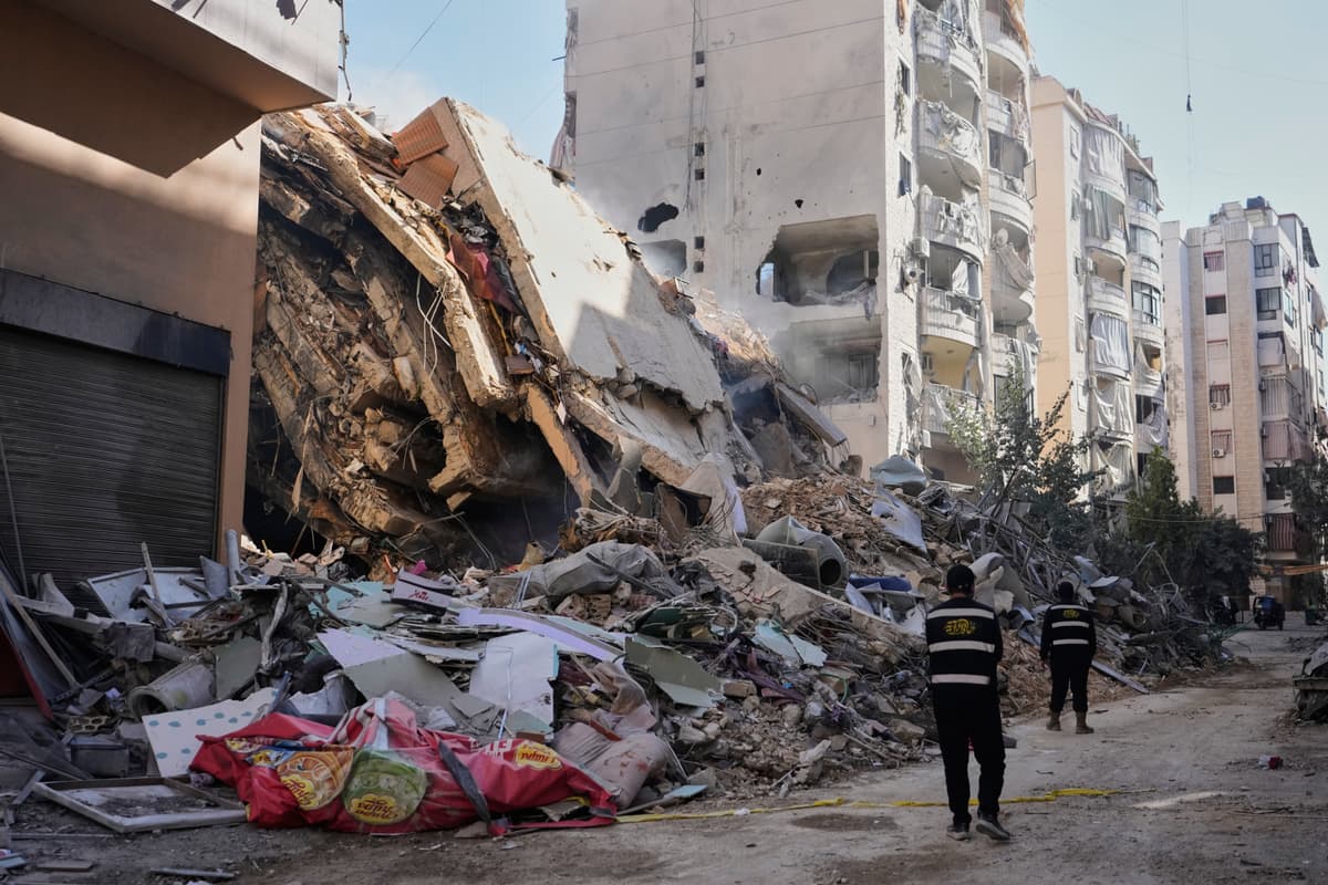 Hezbollah members walk past a building destroyed by an Israeli airstrike in Dahiyeh, Beirut's southern suburbs, Lebanon, March 5, 2026. 