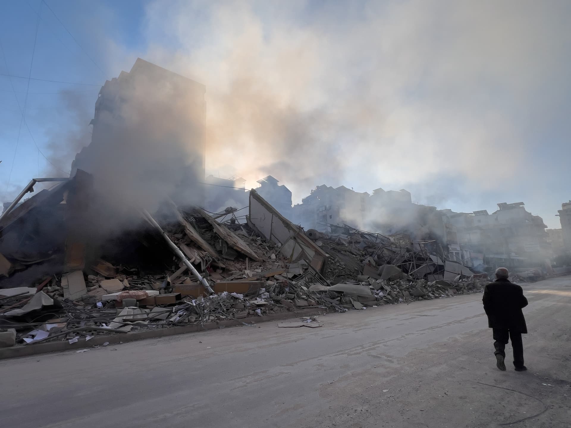 A man passes in front of a destroyed building that housed a branch of Al-Qard Al-Hassan, a non-bank financial institution run by Hezbollah, which was hit by an Israeli airstrike in Dahiyeh, Beirut's southern suburbs, Lebanon, March 10, 2026. 