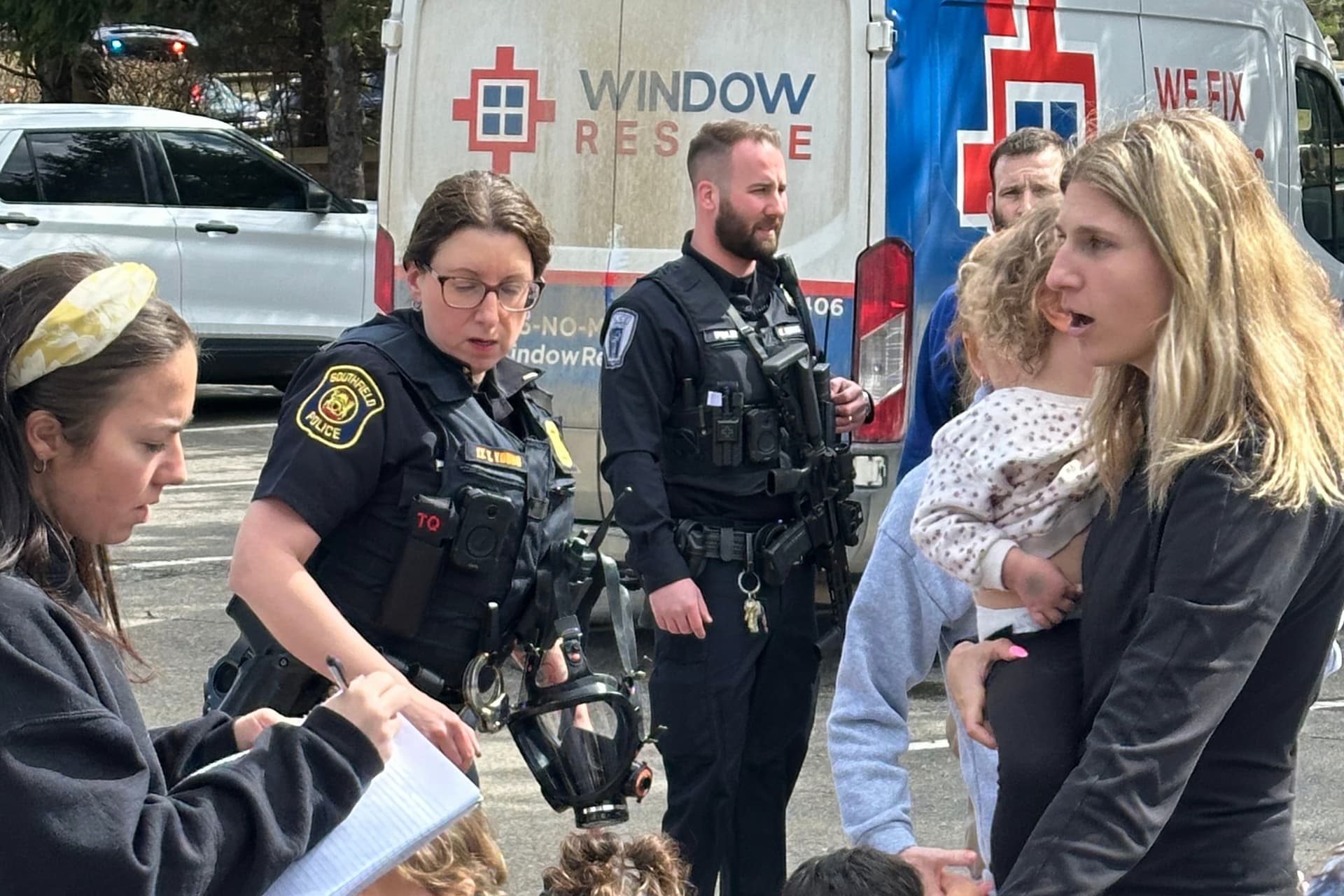 A woman gathers children as law enforcement officers respond to an attack on Temple Israel Synagogue at West Bloomfield, Michigan, on March 12, 2026.