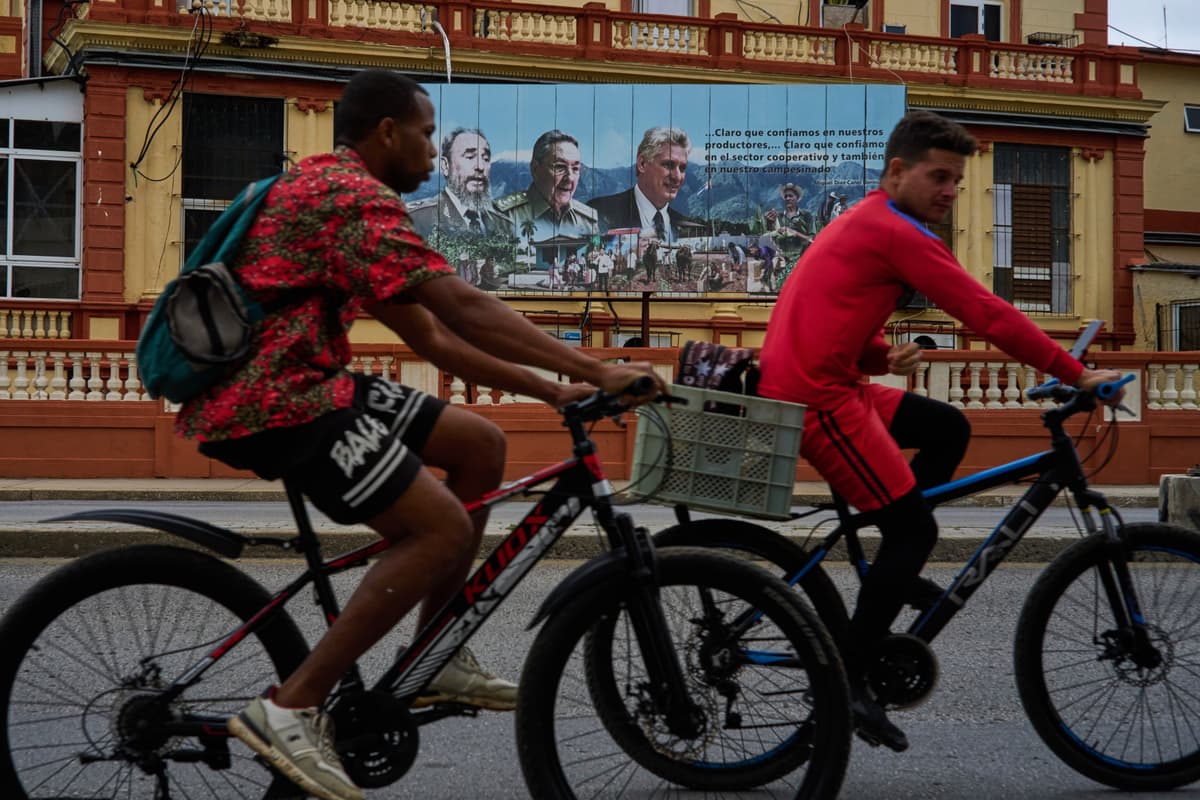 Cyclists pass in front of images of Cuba’s past presidents, Fidel Castro and Raul Castro, and its current president, Miguel Diaz-Canel, at Havana on March 18, 2026.