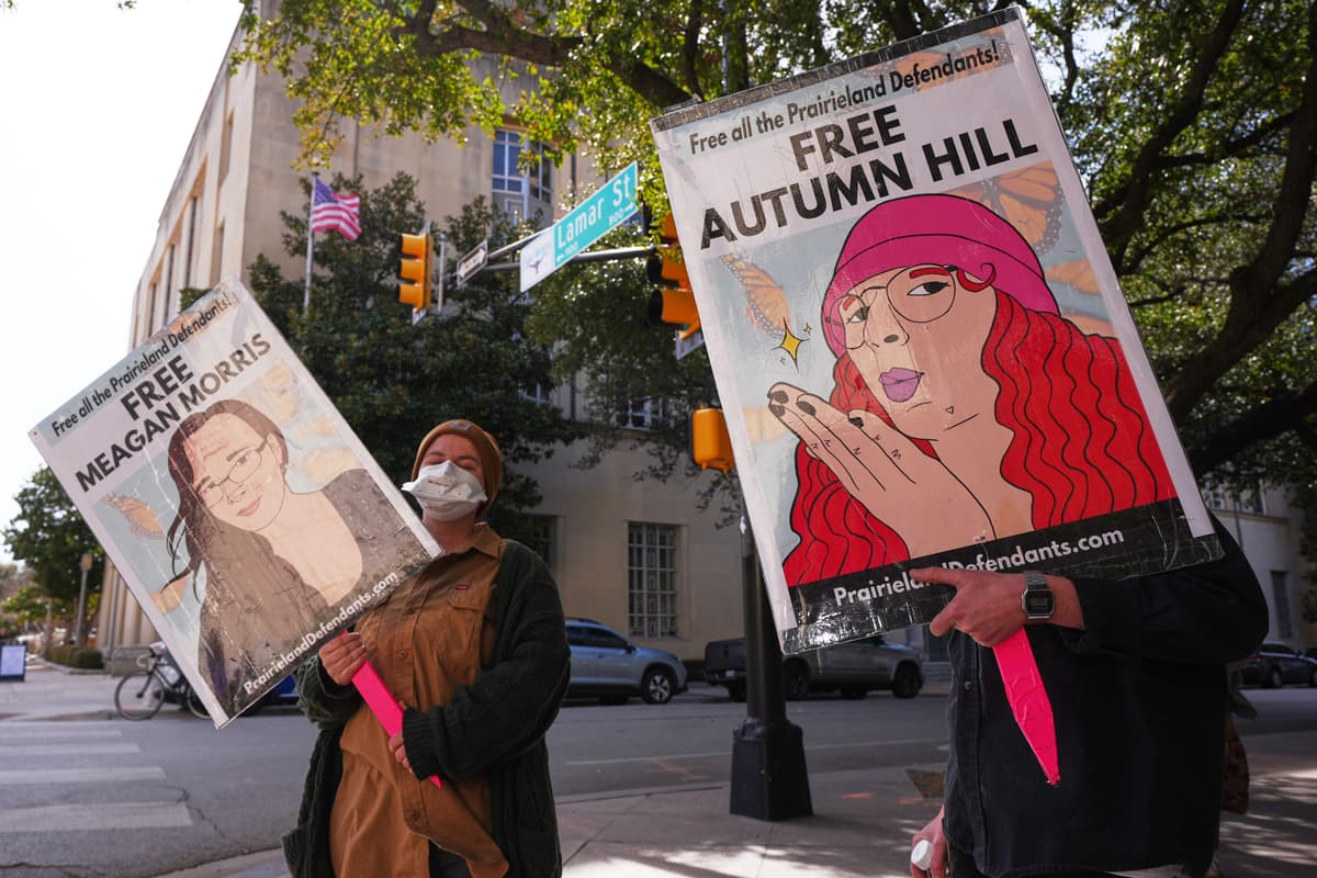 People hold signs outside a federal courthouse at Fort Worth, Texas, on February 23, 2026, during a trial for nine people connected to a 2025 shooting outside an ICE detention facility.