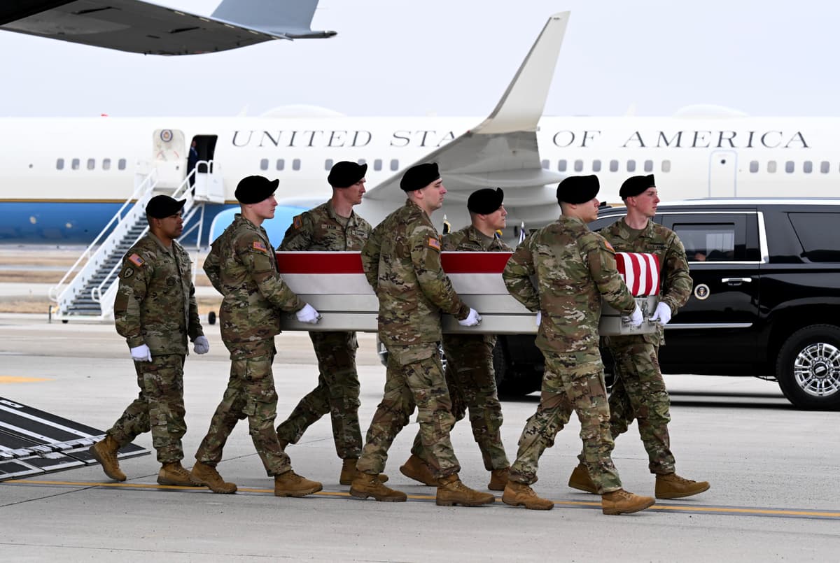 A U.S. Army carry team moves a flagged-draped transfer case containing the remains of Captain Cody A. Khork at Dover Air Force Base on March 07, 2026, with Air Force One in the background.