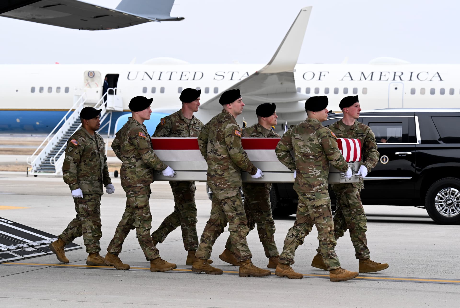 A U.S. Army carry team moves a flagged-draped transfer case containing the remains of Captain Cody A. Khork at Dover Air Force Base on March 07, 2026, with Air Force One in the background.