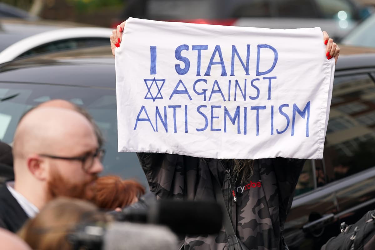 A protester shows a banner at Golders Green in London, Monday, March 23, 2026 after an apparent arson attack on four vehicles belonging to a Jewish ambulance service, Hatzola Northwest, in London.