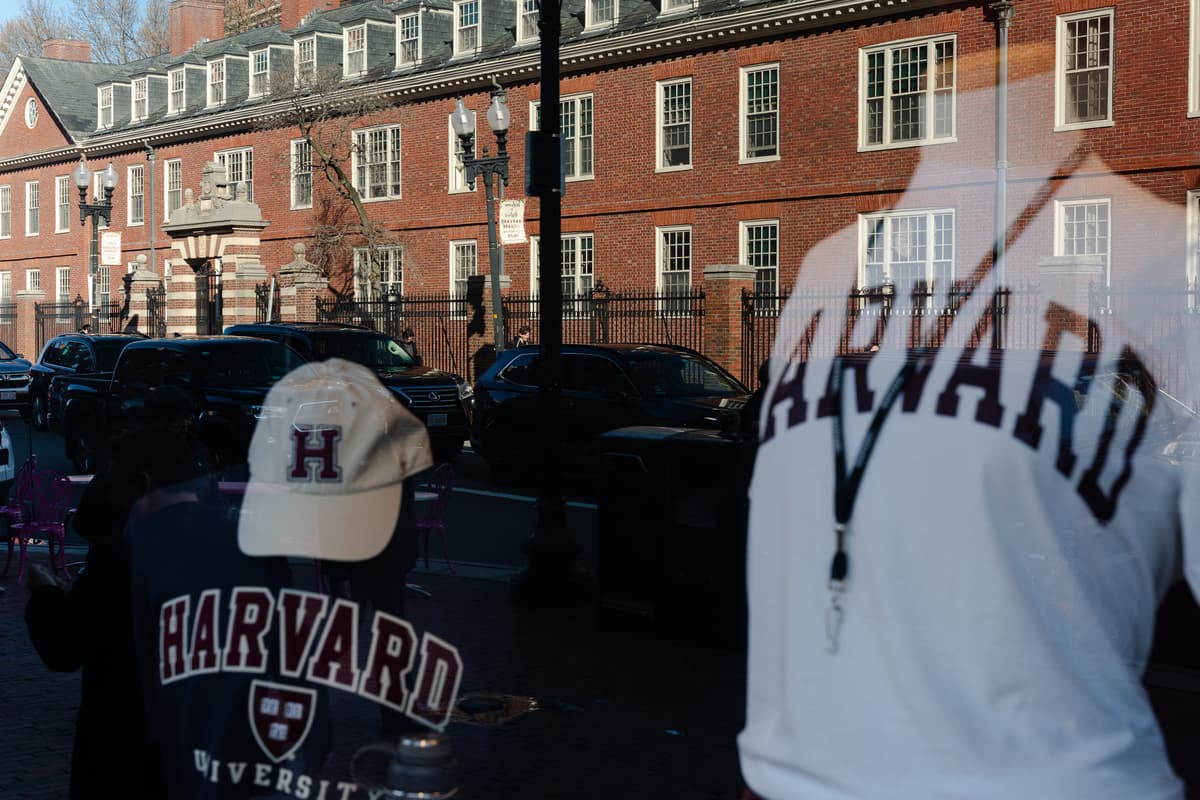 Harvard University is reflected in the window of a merchandise store across the street from the campus at Cambridge, Massachusetts, on April 17, 2025.