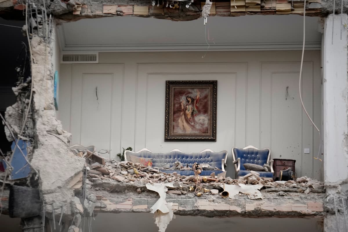 Rubble covers the furniture of a destroyed living room in a residential building hit in an earlier U.S.-Israeli strike in Tehran, Iran, March 23, 2026.