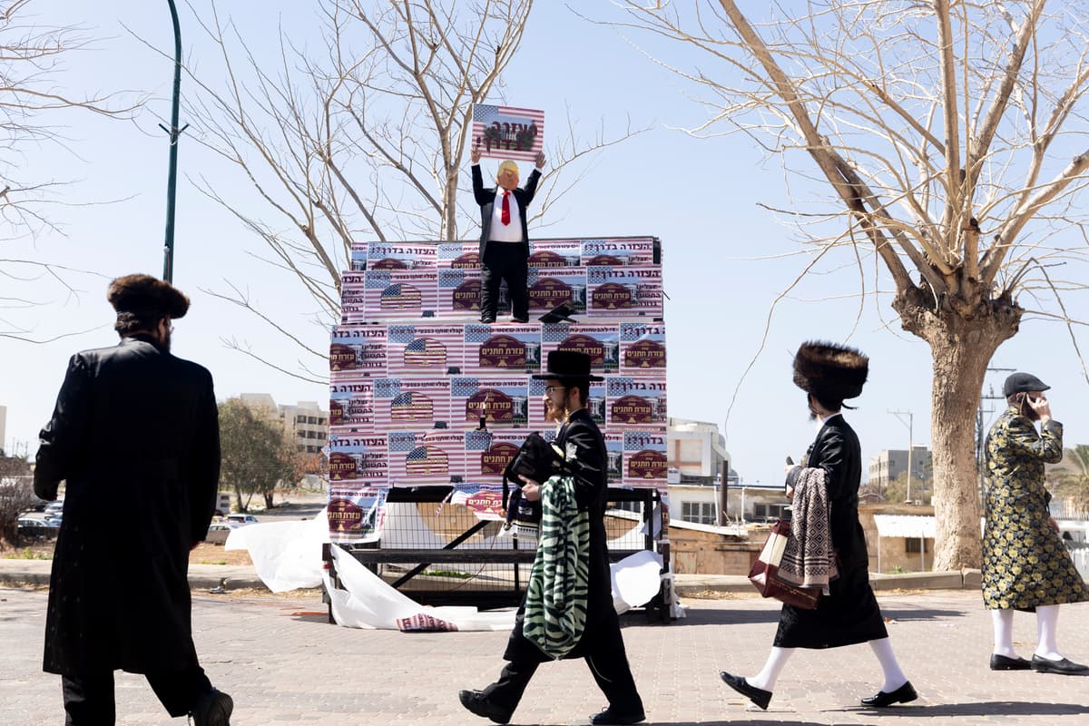 Ultra Orthodox Jewish men walk by an effigy of President Trump holding a sign saying 'Health is on the way' during the Jewish holiday of Purim amid the war with Iran on March 3, 2026 in Netanya, Israel.