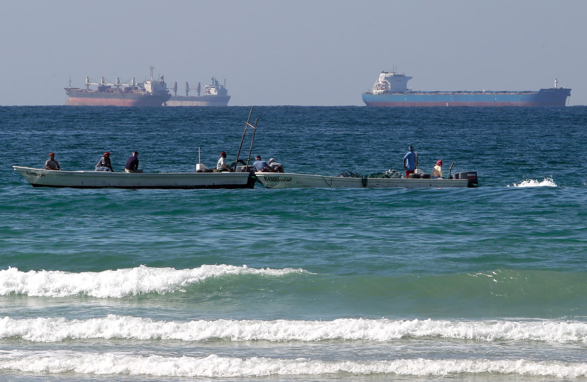 Fishermen work in front of oil tankers south of the Strait of Hormuz.