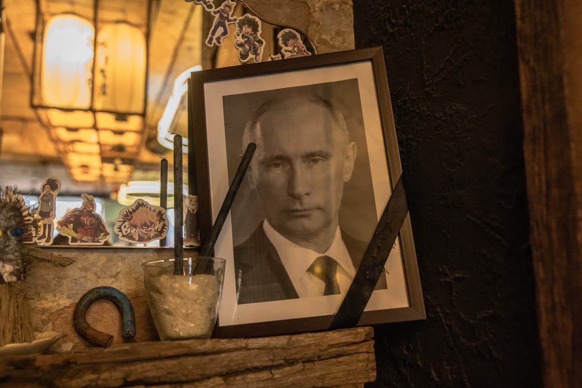 A portrait of Russia's President Vladimir Putin, with a black ribbon over it commonly used for the deceased, is placed next to voodoo dolls, at a restaurant on March 18, 2023 in Kyiv, Ukraine.  