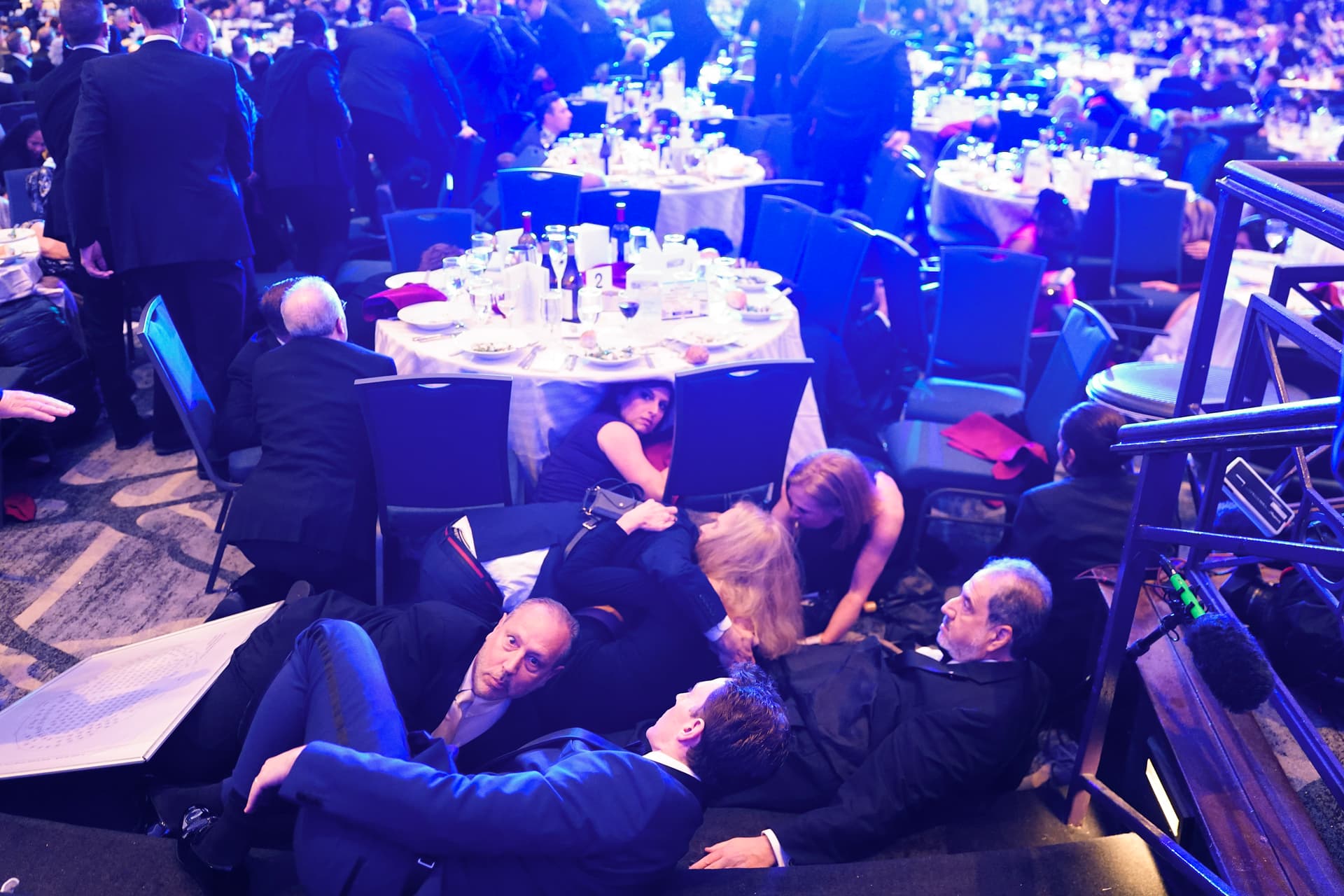Guests take cover after a shooting at the White House Correspondents Dinner where President Trump was to speak on April 25, 2026, at Washington, D.C. President Donald Trump, along with other government officials, were evacuated from the Washington Hilton after the suspected shooter, Cole Allen, was subdued by the Secret Service.