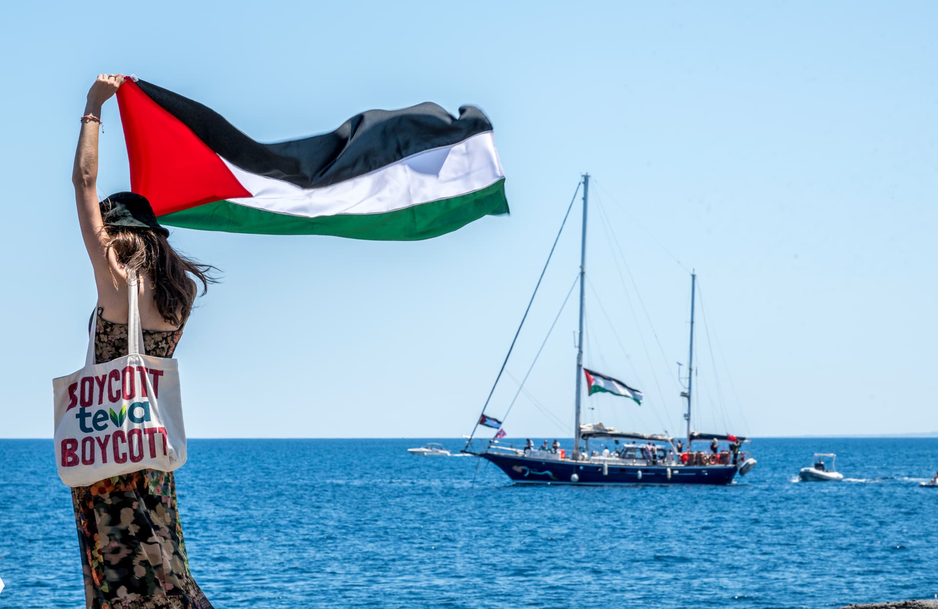 A woman raises the Palestinian flag shortly before a ship sets sail for Gaza. 