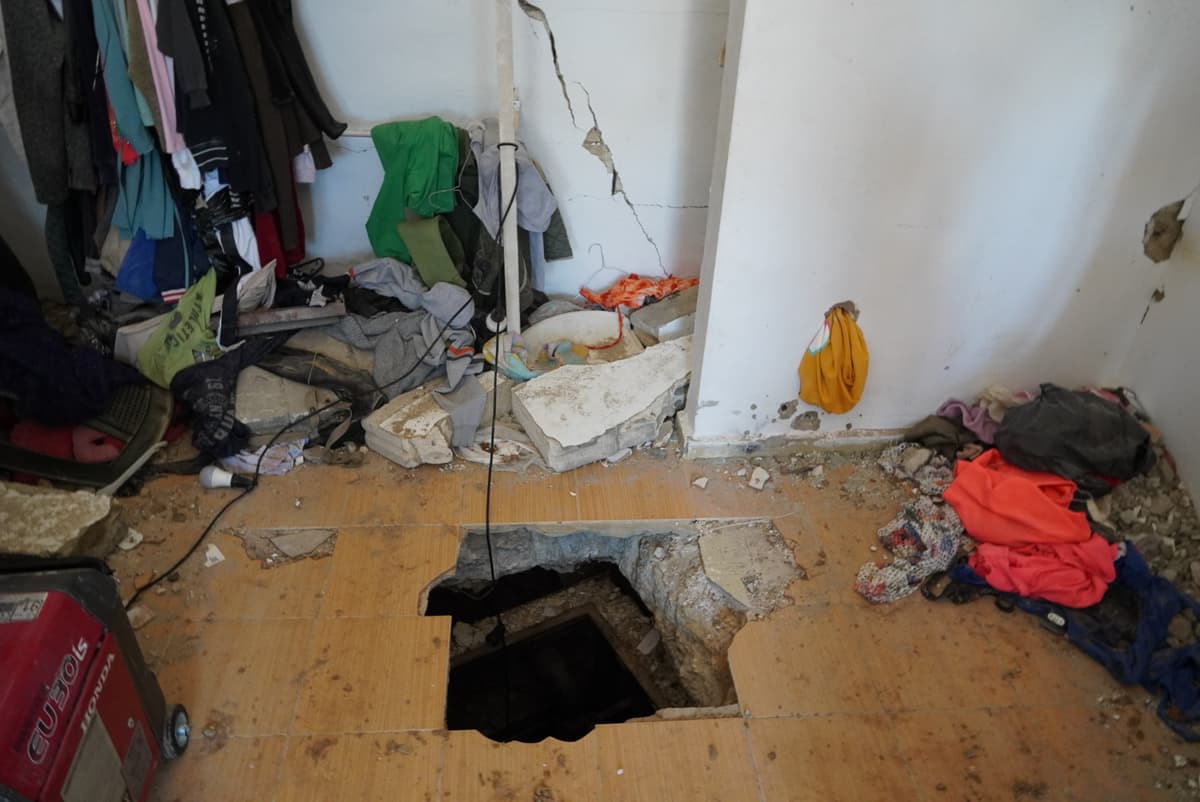 The opening in the floor is roughly the size of two floor tiles by two. To descend into the pitch-dark shaft, one climbs down a metal ladder to a small landing, where a spiral metal staircase continues deeper into the tunnel.