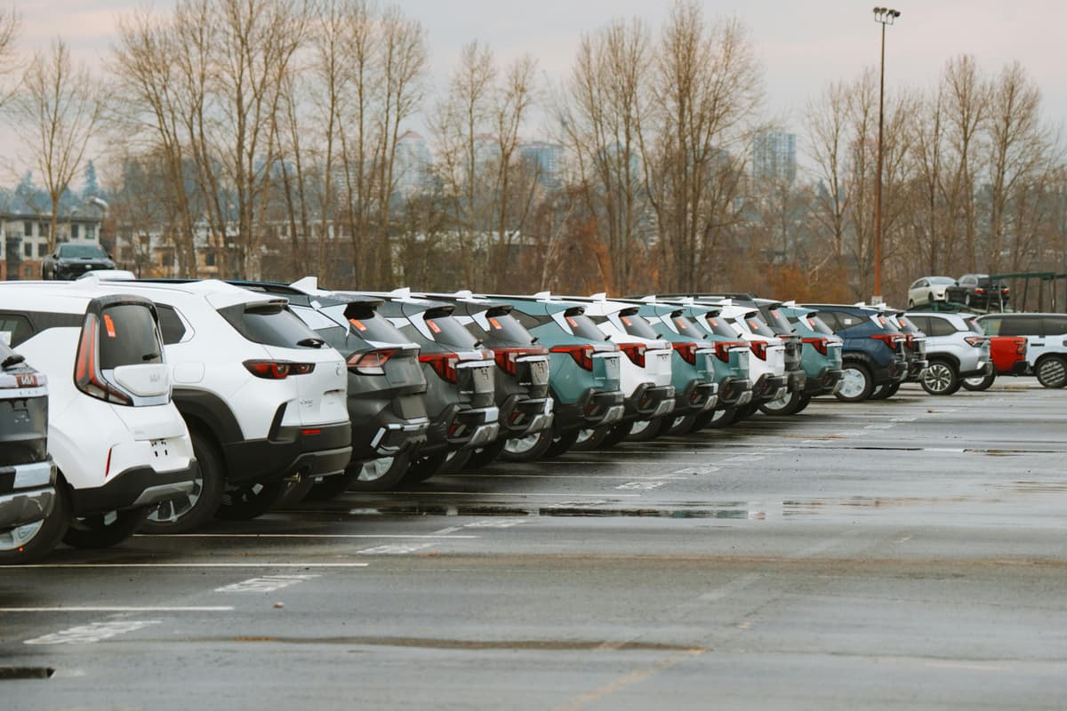 A line of parked cars in an outdoor urban parking lot .