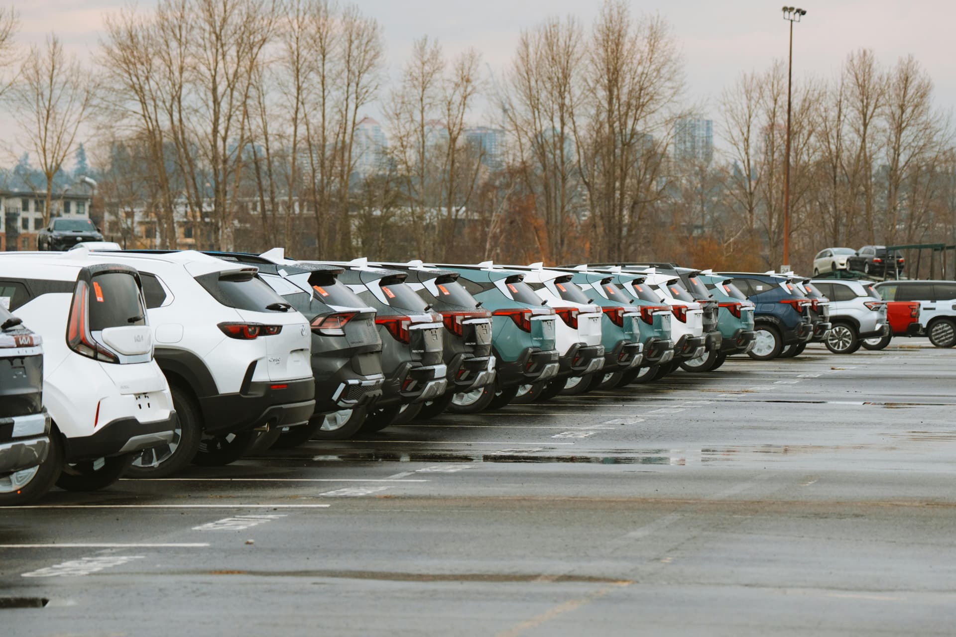 A line of parked cars in an outdoor urban parking lot .