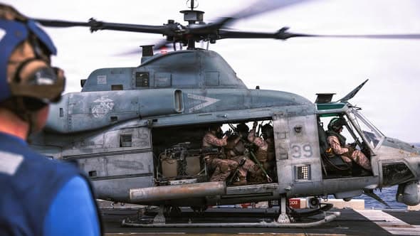 In this photo released June 9, 2026, U.S. Marines with the 31st Marine Expeditionary Unit load onto a UH-1Y Venom aboard USS Tripoli (LHA 7) to conduct aerial sniper and close air support training while transiting regional waters.