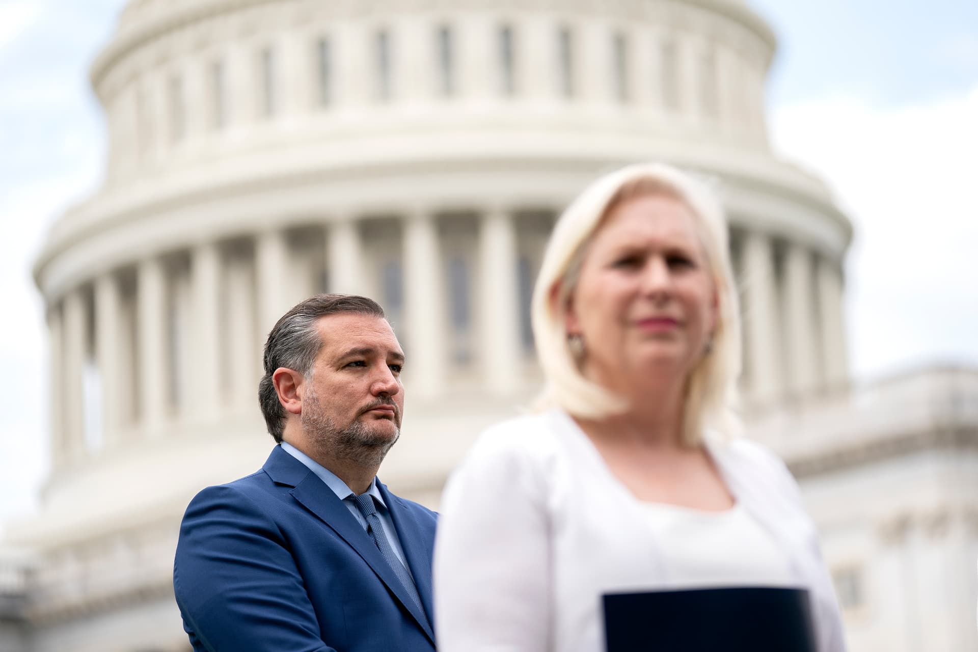 Senator Ted Cruz and Senator Kirsten Gillibrand listen during a news conference outside the Capitol.