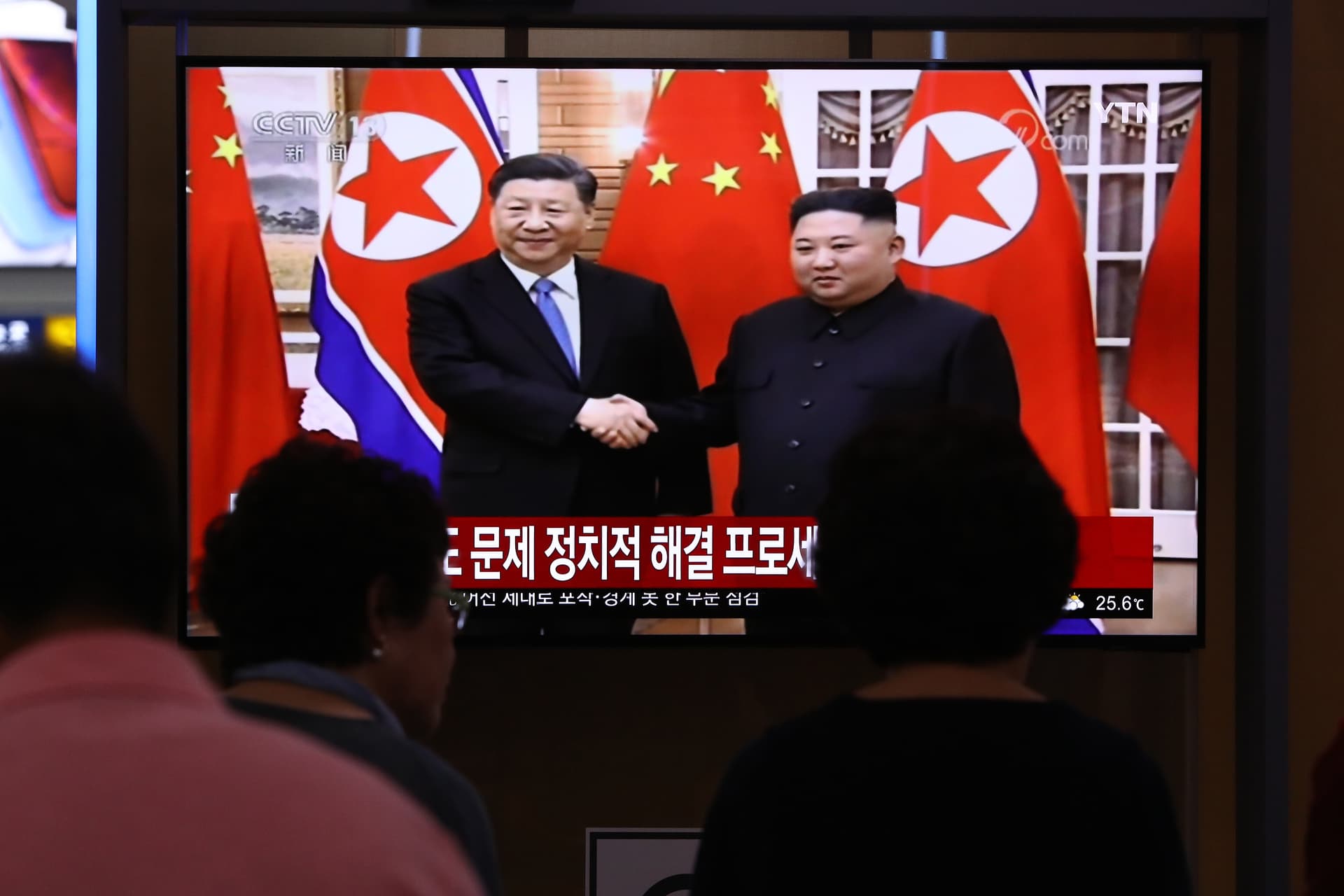 South Koreans watch on a screen showing Kim Jong-un shaking hands with President Xi Jinping at the Seoul Railway Station on June 20, 2019.