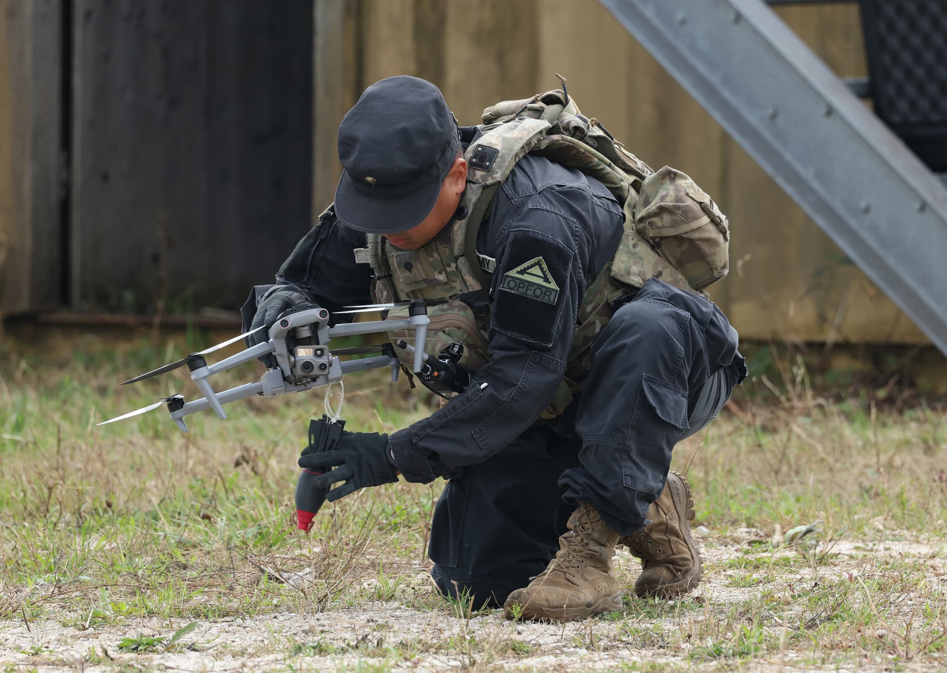 A member of the U.S. Army 7th Army Training Command, clad in black in the role of opposition force, prepares an Autel FPV drone carrying live training bomblets during a demonstration for the media at the Saber Junction 26 combined military exercise at the U.S. Army Joint Multinational Readiness Center on August 26, 2026, near Hohenfels, Germany. The U.S. military is testing and acquiring a wide range of drone capabilities in response to the new combat realities born out of the ongoing Russian war in Ukraine. 