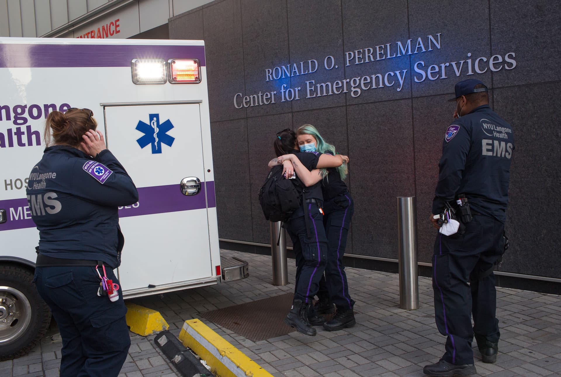 EMT paramedics hug outside the emergency room of NYU's Langone Hospital at New York CIty.