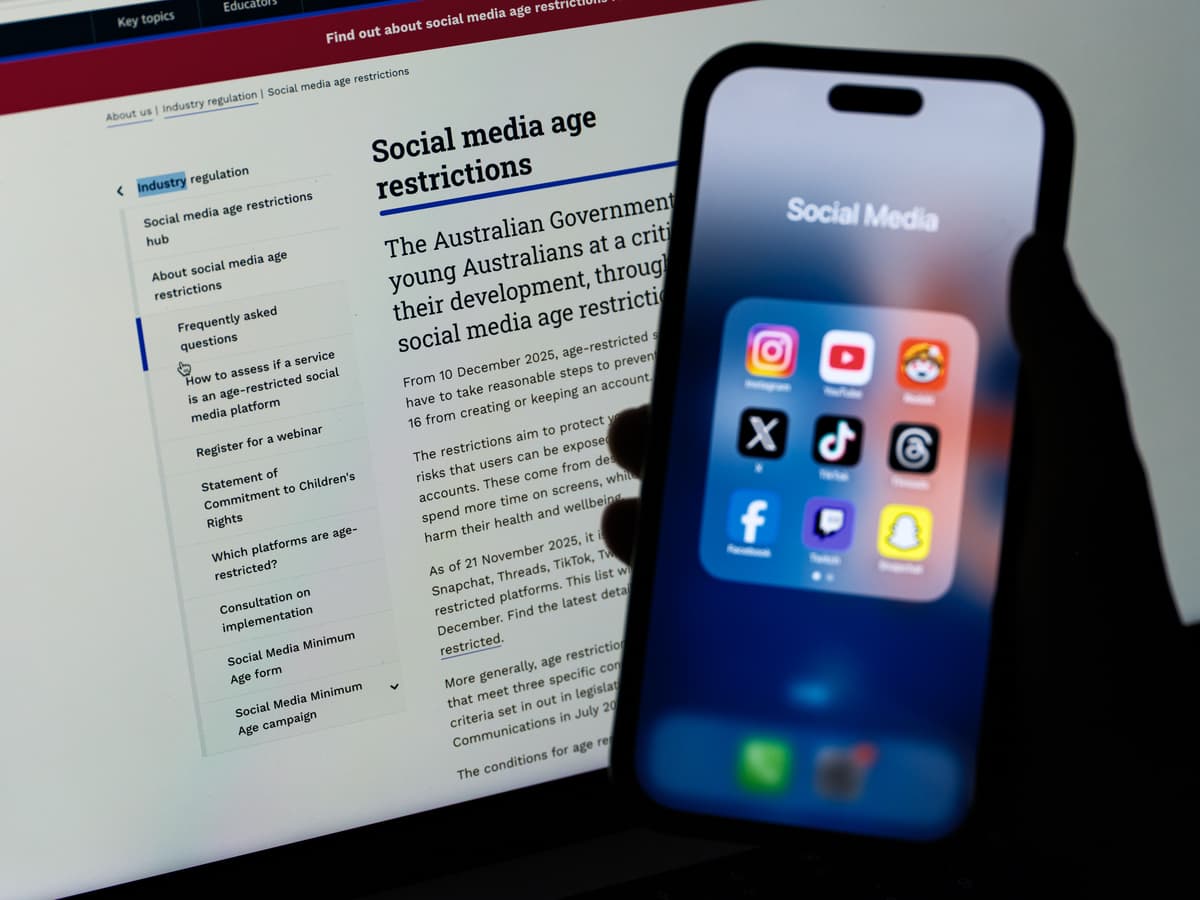 Social media networking apps are displayed on a phone with the eSafety Commissioner website displayed in the background at Sydney, Australia, on December 7, 2025. 