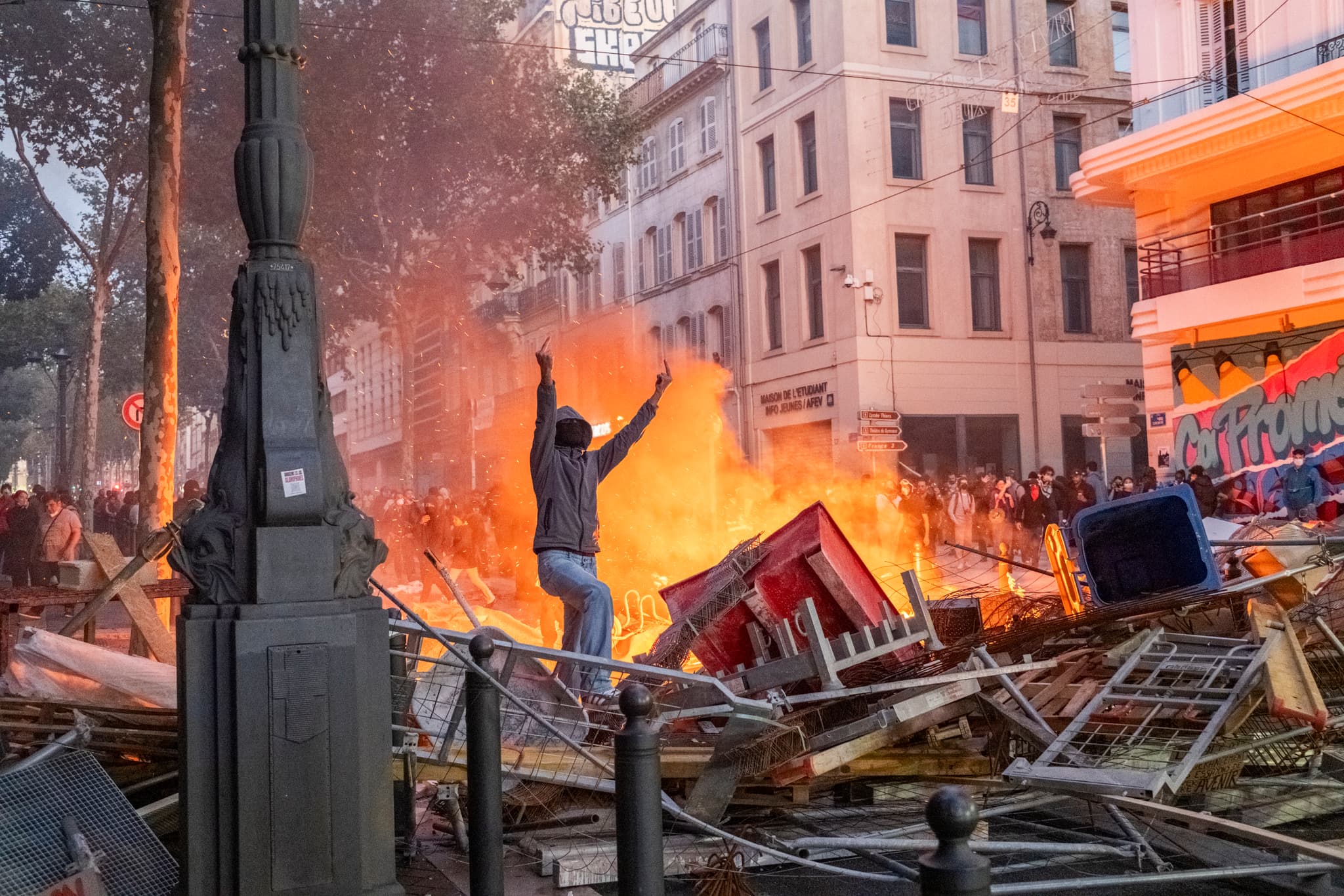 A protester gives the police the middle finger from between barricades on October 17, 2026, at Marseille, France.