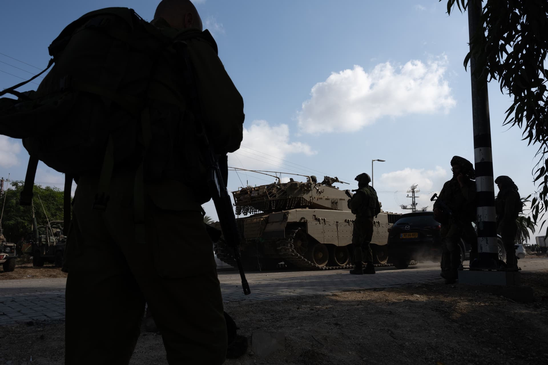 Soldiers walk past tanks on October 10, 2023, outside of Kibbutz Kfar Aza where three days earlier Hamas terrorists had killed 62 to 64 residents.