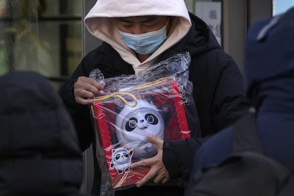 A man holds a Bing Dwen Dwen doll purchased from a store selling 2022 Winter Olympics memorabilia in Beijing, February 7, 2022. AP/Andy Wong