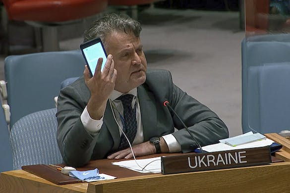 Ukraine's ambassador to the United Nations, Sergiy Kyslytsya, holds up a phone as he speaks at an emergency meeting of the U.N. Security Council February 23, 2022. UNTV via AP