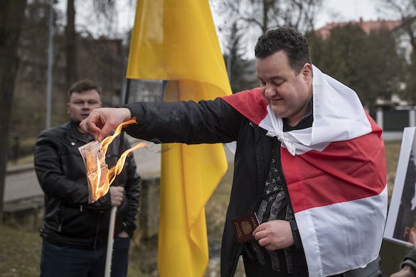In front of the Russian embassy at Vilnius, Lithuania, a citizen of Belarus and Russia, Timote Suladze, burns a Russian passport February 24, 2022. AP/Mindaugas Kulbis, file