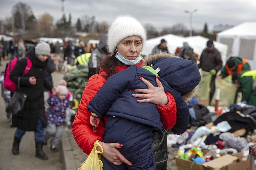 A woman carries her child as she arrives at the Medyka border crossing, Poland, after fleeing from Ukraine February 28, 2022. AP/Visar Kryeziu