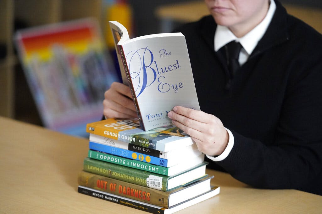 The Utah Pride Center's Amanda Darrow poses with books that have been the subject of complaints from parents at Salt Lake City. AP Photo/Rick Bowmer, File